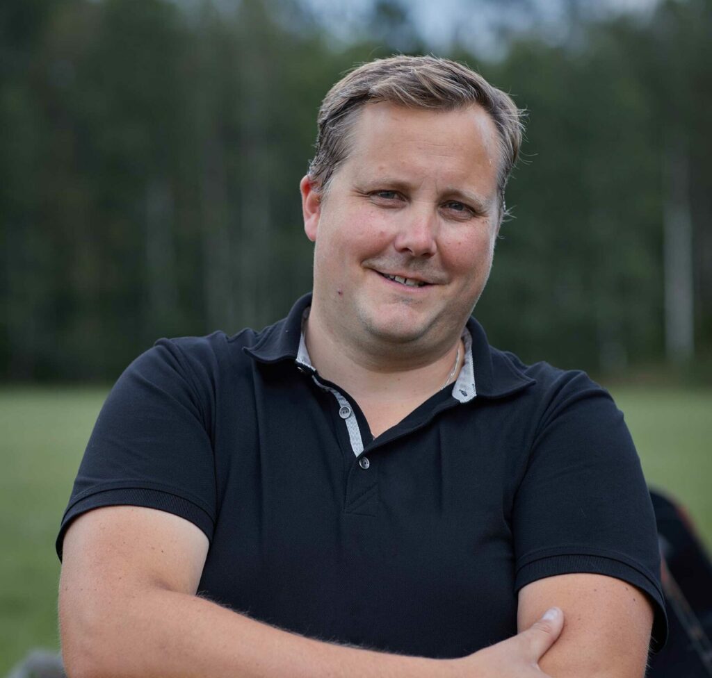 man smiling with a black shirt standing on a field in Sweden