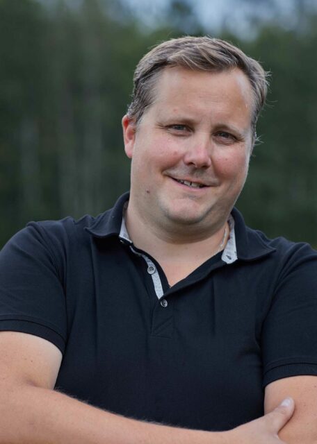 man smiling with a black shirt standing on a field in Sweden