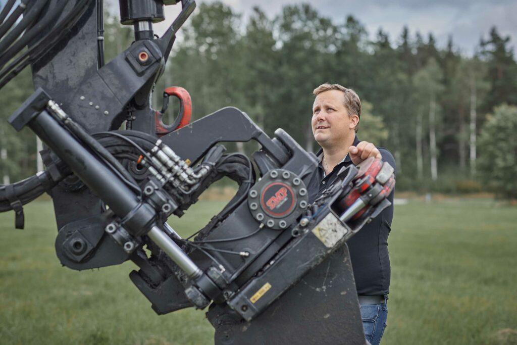 Man admiring his excavator and tiltrotator from SMP on a field in Sweden