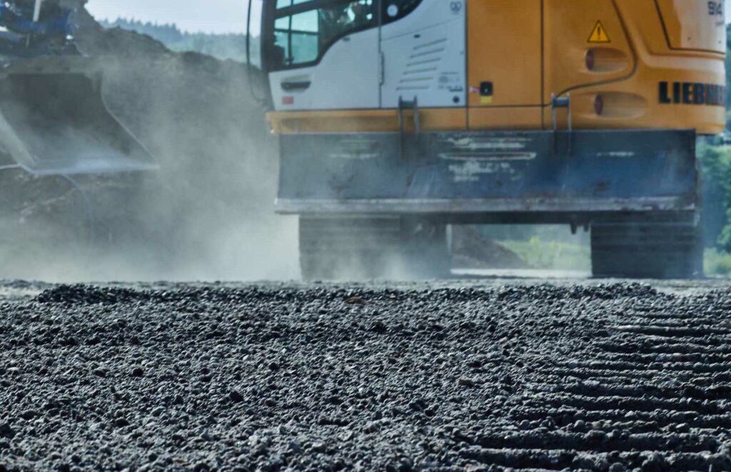 excavator with large excavator bucket on top of gravel