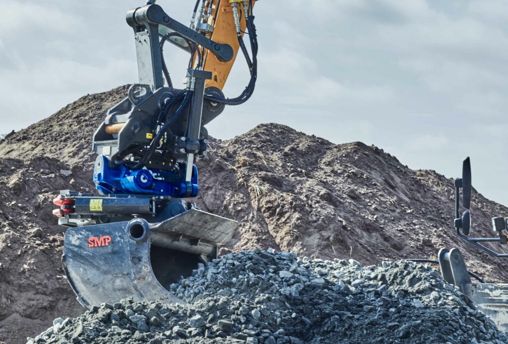 Excavator bucket performing heavy lifting of gravel in a cloudy day in Sweden