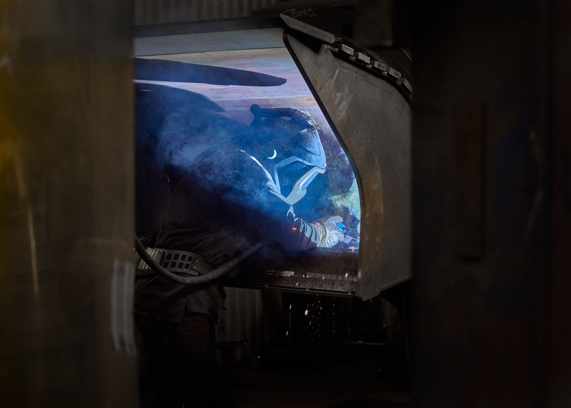 Welder doing some work on an excavator bucket in an industrial area