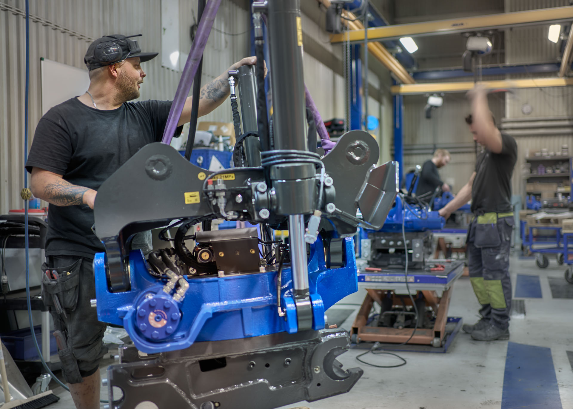 Three men in Sweden doing some work on tiltrotators in the manufacturing area